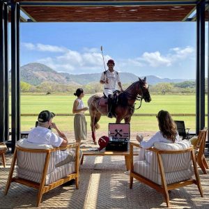 group sits while watching polo player ride horse